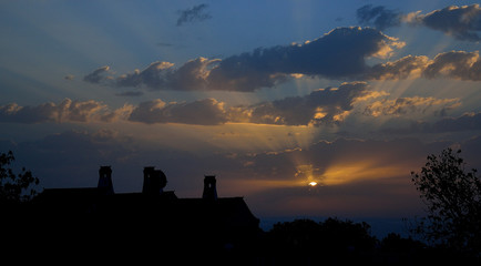 Awesome sky at sunrise with scattered clouds and backlit country house
