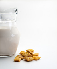 Una jarra de cristal junto a unos cereales rellenos de chocolate vistos frontalmente