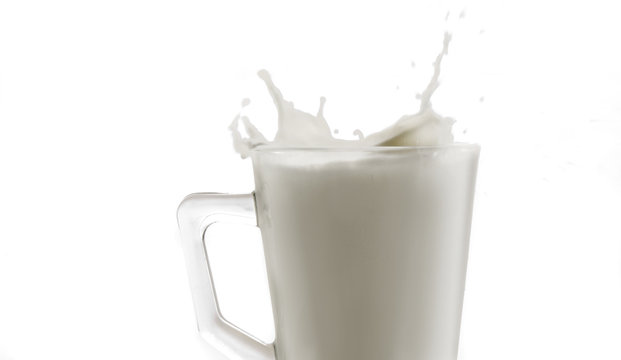 Detalle de un vaso de cristal con un salpic&oacute;n de leche sobre un fondo blanco 2