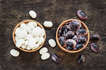 white and dark beans on a dark wooden background in a cup