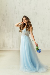 Fototapeta na wymiar Beautiful model in a blue dress whith flower at the white background