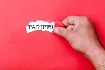 Tariffs word behind ripped piece of paper