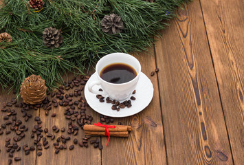 Obraz na płótnie Canvas A cup of coffee with cinnamon and fir branches on a wooden background, New Year's holidays, a place for an inscription, christmas
