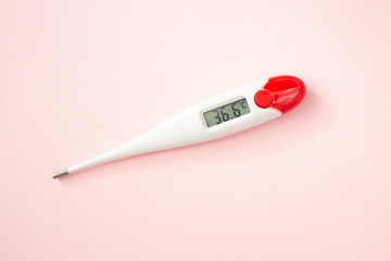 White digital clinical thermometer on pink background shows normal temperature