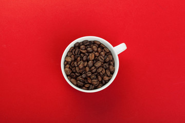 Coffee cup with coffee beans on red background.