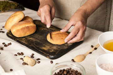 Women's hands cutting fresh bun on vintage black cutting board