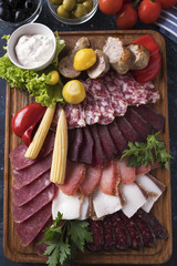 Different sausages with pickled vegetables on wooden board. Top view