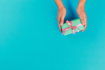 Woman holding gift box on color background