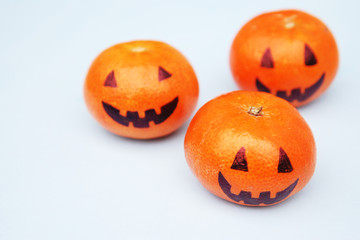 Funny orange mandarins or tangerines pumpkin painted in the form of icons of Halloween on the light backround