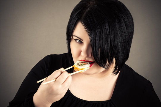 fat woman eating sushi and rolls 
