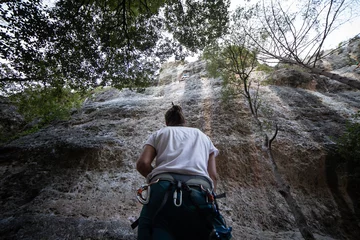 Foto op Plexiglas From below of anonymous man in harness looking up at mountain and checking partner climbing cliff   © pablobenii