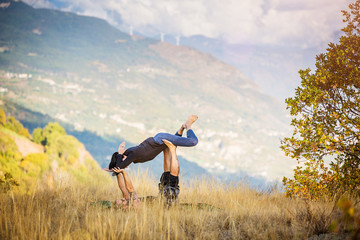Giovane coppia pratica acroyoga e yoga all'aperto in montagna al parco
