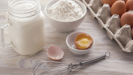 Fototapeta na wymiar Ingredients for baking on a white wooden table. Ingredients - flour, eggs, milk, yolk. Bakery concept