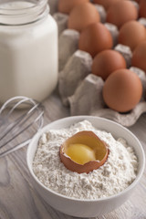 Bakery ingredients - flour, eggs, milk, yolk on a table. Sweet pastry baking concept. Closeup