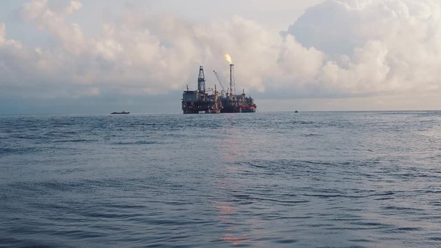 FPSO tanker vessel near Oil Rig platform. Offshore oil and gas industry. Flare is burning with smoke. Environmental pollution