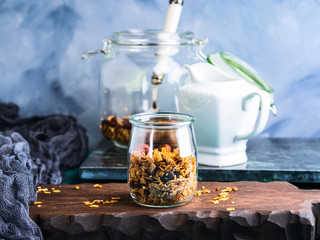Homemade granola with honey, raisins, cherries, sesame and chestnuts in a glass on wooden board