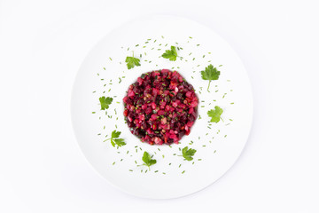 Salad with beets. Vinegret is a traditional Russian salad made from beets and vegetables in a white plate. The background is white. Top view. Copy space. Horizontal shot.