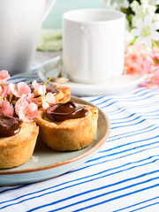 Cakes with frangipane, cherry jam and chocolate frosting. Romantic table setting with flowers. Mother's day card