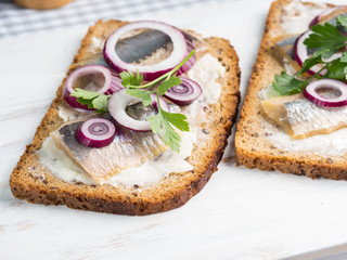 Danish open sandwich smorrebrod with salted herrings, red onion, butter. Traditional snack