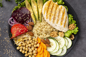 Bowl of Buddha, The concept of a healthy diet: grilled chicken, avocado, chickpeas, kinua, carrots, tomatoes, nuts. Balanced food. Top view. Copy space.