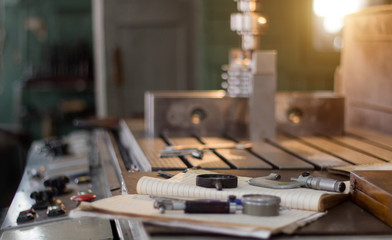 A private workshop for working with metal parts, in the background a drilling machine drills a hole in the pulley, on the table lie measuring instruments
