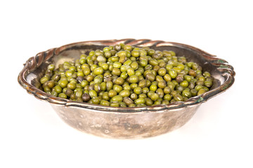 Lot of whole dry green mung beans in old iron bowl isolated on white background