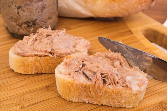 Two Homemade Rillettes French meat spread made of pork on baguette bread and knife spreading the Rillettes
