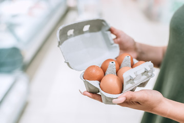 Closeup photo of a girl holding cardboad box with eggs.