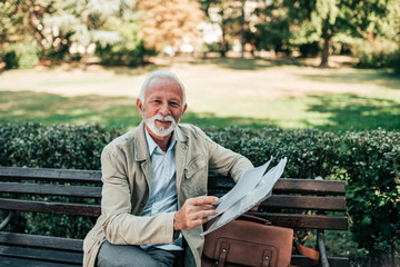 Portrait of a senior man reading newspapers in the park.