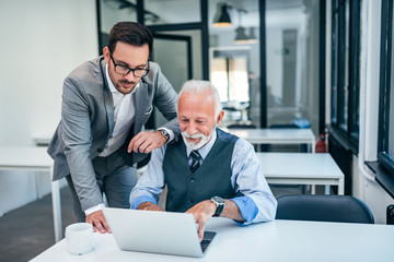 Young man working with boss or older employee in the office.