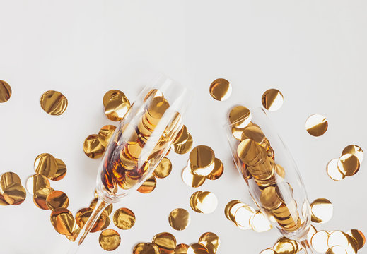 Golden confetti in champagne glasses on the white background.