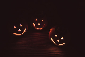 three glowing pumpkin faces for Halloween on wooden background. the symbol of Halloween