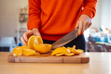 Woman cutting, peeling oranges preparation concept in home kitchen  