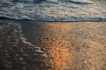 Fototapeta na wymiar sunset at sea, bottom view, sand at sunset, waves with foam