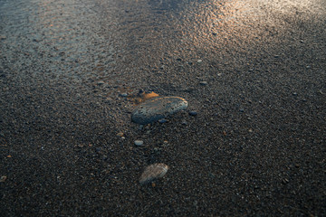 sunset at sea, bottom view, sand at sunset, stone on the sand