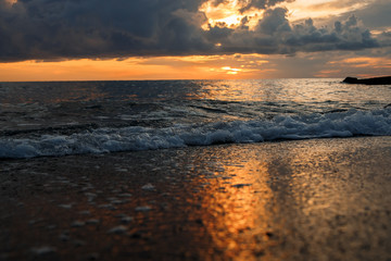 sunset at sea, bottom view, sand at sunset, waves with foam