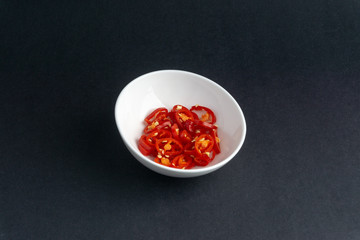 Red chili slices on dark background with selective focus and crop fragment