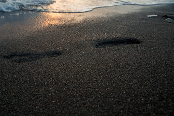 Footprints on the sea sand at sunset