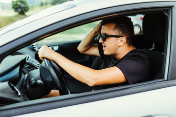 Young man driving a car shocked about to have traffic accident, window view