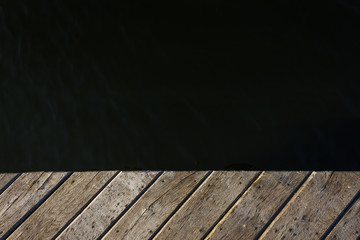 Fragment of an old wooden pier on the background of water. Copy space. Background 