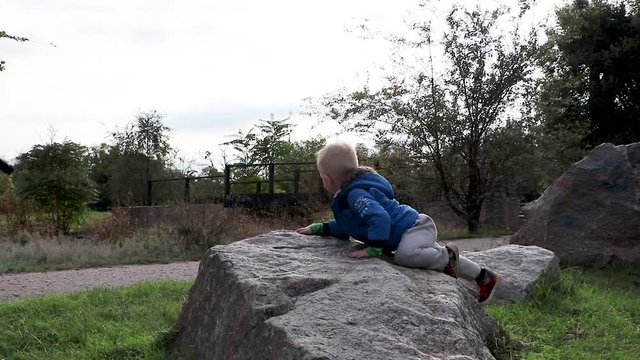 The child dismounts from a granite stone.