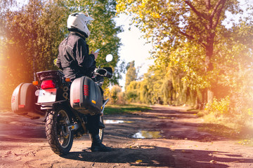 Motorbiker travelling, autumn day, motorcycle off road, rider, adventurer, extreme tourism, cold weather clothes, yellow forest, copy space, light tinting
