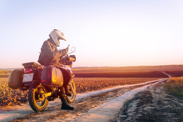 Motorbiker travelling, autumn day, motorcycle off road, rider, adventurer, extreme tourism, cold weather clothes, uses smartphone, internet, search, light tinting