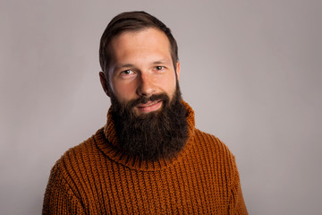 Young long thick beard man studio shot portrait. Handsome in warm knitted sweater. Copy space dark...