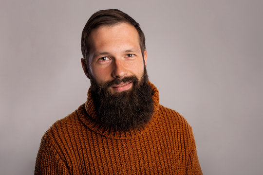 Young long thick beard man studio shot portrait. Handsome in warm knitted sweater. Copy space dark grey background