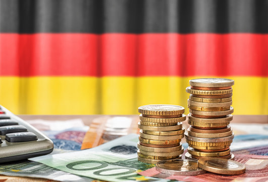 Geldscheine und M&uuml;nzen vor der Nationalflagge Deutschlands
