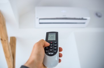 Man adjusting and regulating temperature on home air conditioner