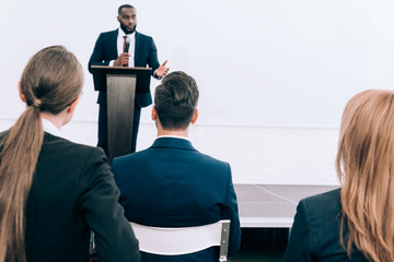 handsome african american speaker talking in front of audience conference hall