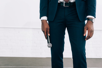 cropped image of african american businessman holding microphone during seminar in conference hall