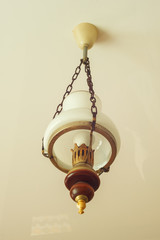 Retro chandelier (white glass) suspended on chains to the ceiling. Close-up
